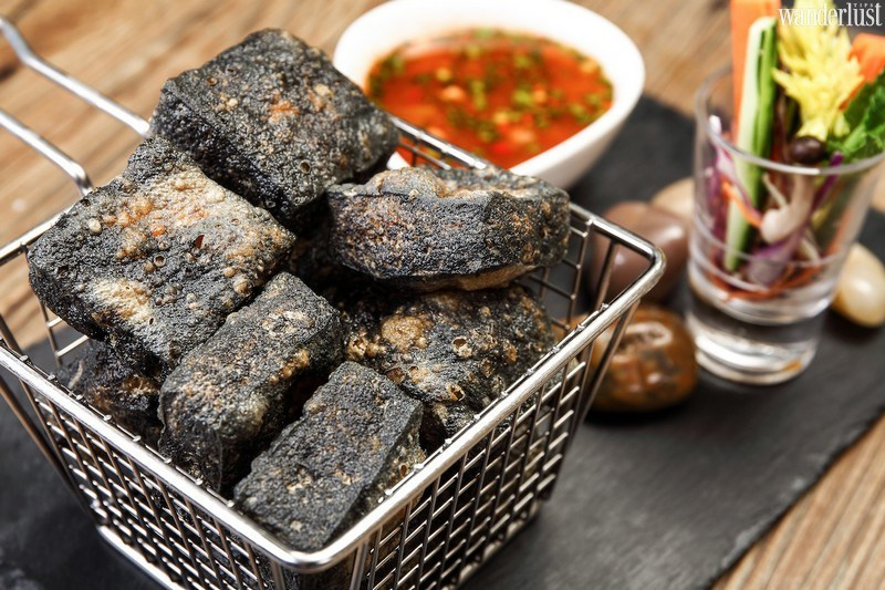 Từng miếng đậu phụ đen xì vừa vớt ra từ bếp lửa còn nguyên hơi nóng, xiên thêm lỗ nhỏ để dầu mè cùng sốt ớt quyện vào đậm thêm hương vị ngon đến khó tả.