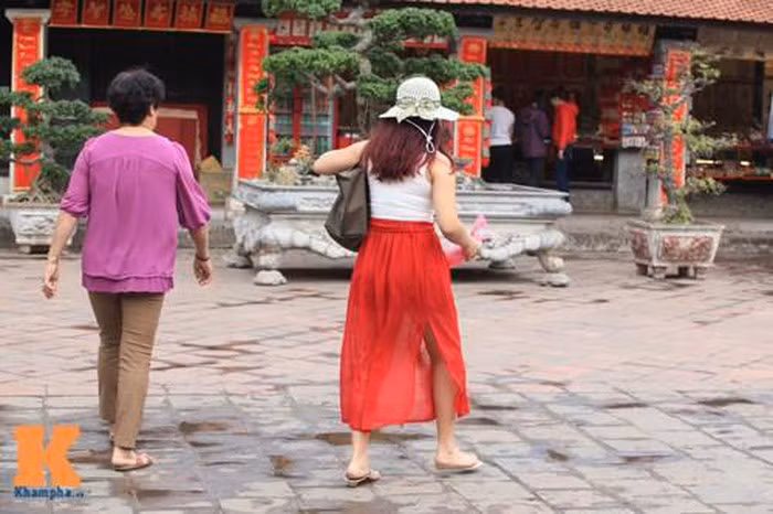 Cô gái đi lễ chùa với chiếc váy mỏng lòe loẹt và có đường xẻ cao. Ảnh: Khám phá. Video "Minh Hằng chia sẻ về phong cách thời trang". Nguồn: VTC.