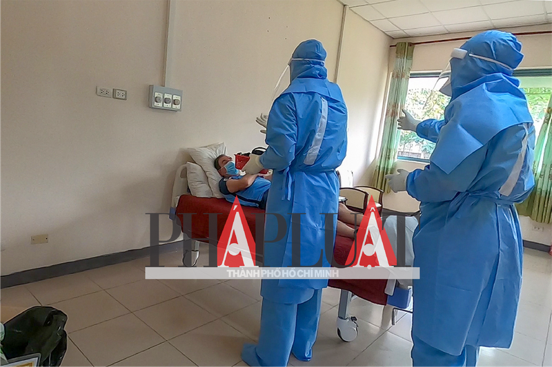 Các y tá tiến hành kiểm tra sức khỏe và thăm hỏi bệnh nhân nghi ngờ nhiễm trước khi đến khu vực có người nhiễm COVID-19. Điều dưỡng Nguyễn Thành Trung cho biết: Nguyên tắc là đi từ phòng nghi nhiễm rồi đến phòng nhiễm, không được làm ngược lại. Ảnh: Pháp Luật TP.HCM.