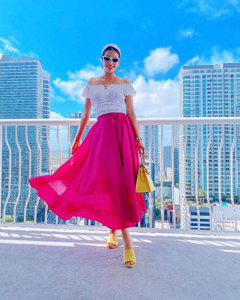 Phạm Hương tỏa sắc rực rỡ khi kết hợp áo trễ vai trắng với chân váy maxi hồng.