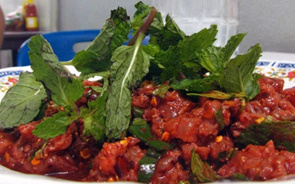 Larb Leuat Neua được làm từ thịt bò sống thái mỏng trộn tiết canh bò và rắc thêm một ít rau húng thơm.