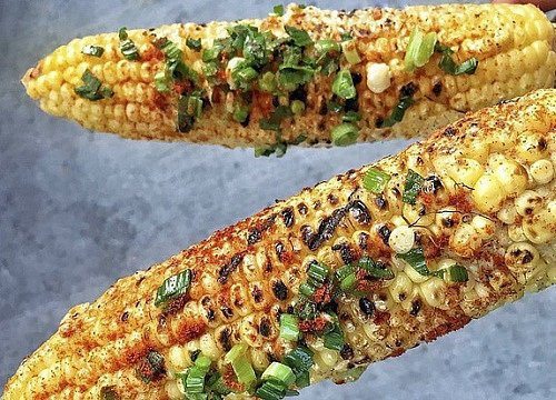 Bắp nướng mỡ hành: Những bắp ngô nướng vàng ươm nằm trên vỉ, có chút xém xém trên bề mặt, cô bán hàng cứ chốc lại lật lên và quét một lượt mỡ hành rồi lại lật xuống. Cái mùi thơm ngon, béo ngậy cứ kéo bạn “sà xuống” vào một hàng quán ngay lập tức.