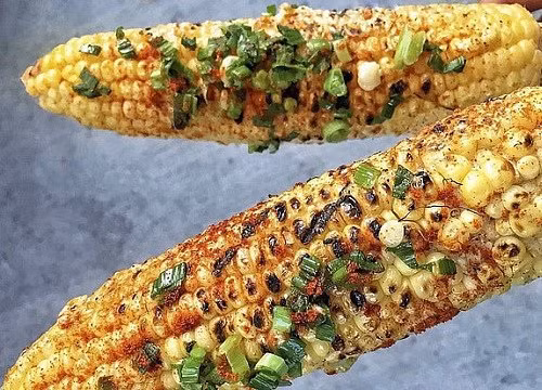 Bắp nướng mỡ hành: Những bắp ngô nướng vàng ươm nằm trên vỉ, có chút xém xém trên bề mặt, cô bán hàng cứ chốc lại lật lên và quét một lượt mỡ hành rồi lại lật xuống. Cái mùi thơm ngon, béo ngậy cứ kéo bạn “sà xuống” vào một hàng quán ngay lập tức.