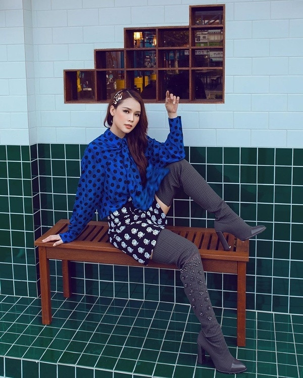 Sam chơi trội với màn kết hợp đầy ngẫu hứng khi diện sơ mi cách điệu họa tiết chấm bi đen trên nền vải xanh cổ điển, phối cùng chân váy hoa và boots đùi.