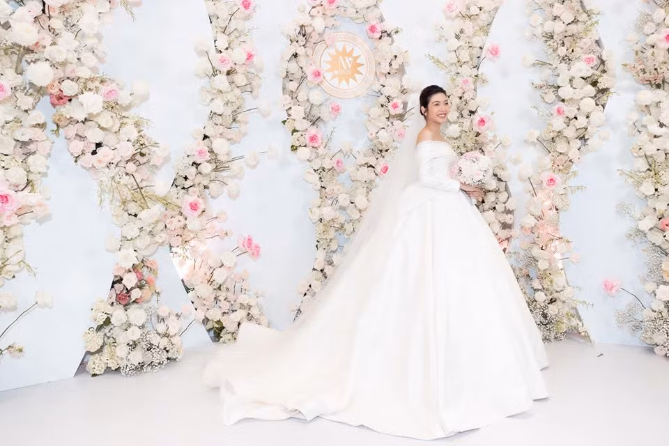 NTK đã sử dụng chất liệu nhập khẩu cao cấp là Satin Duchesse thượng hạng, có màu ánh nhũ Champagne, kết hợp ren Guipure được dệt từ sợi tơ thượng hạng. Để nhấn điểm cho các họa tiết, 2.000 viên đá Swarovski đã được đính chìm trên ren, tạo nên sự lấp lánh, nổi bật mà không hề nặng nề khi mặc.