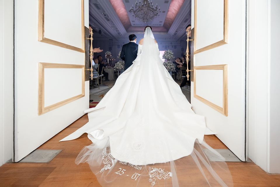 Đặc biệt, chiếc váy cưới của Á hậu Thúy Vân được nhấn bởi phần nơ to bản cách điệu tạo thành đuôi dài sang trọng, dựa trên chia sẻ của chú rể: “Cô dâu chính là một món quà vô giá”.