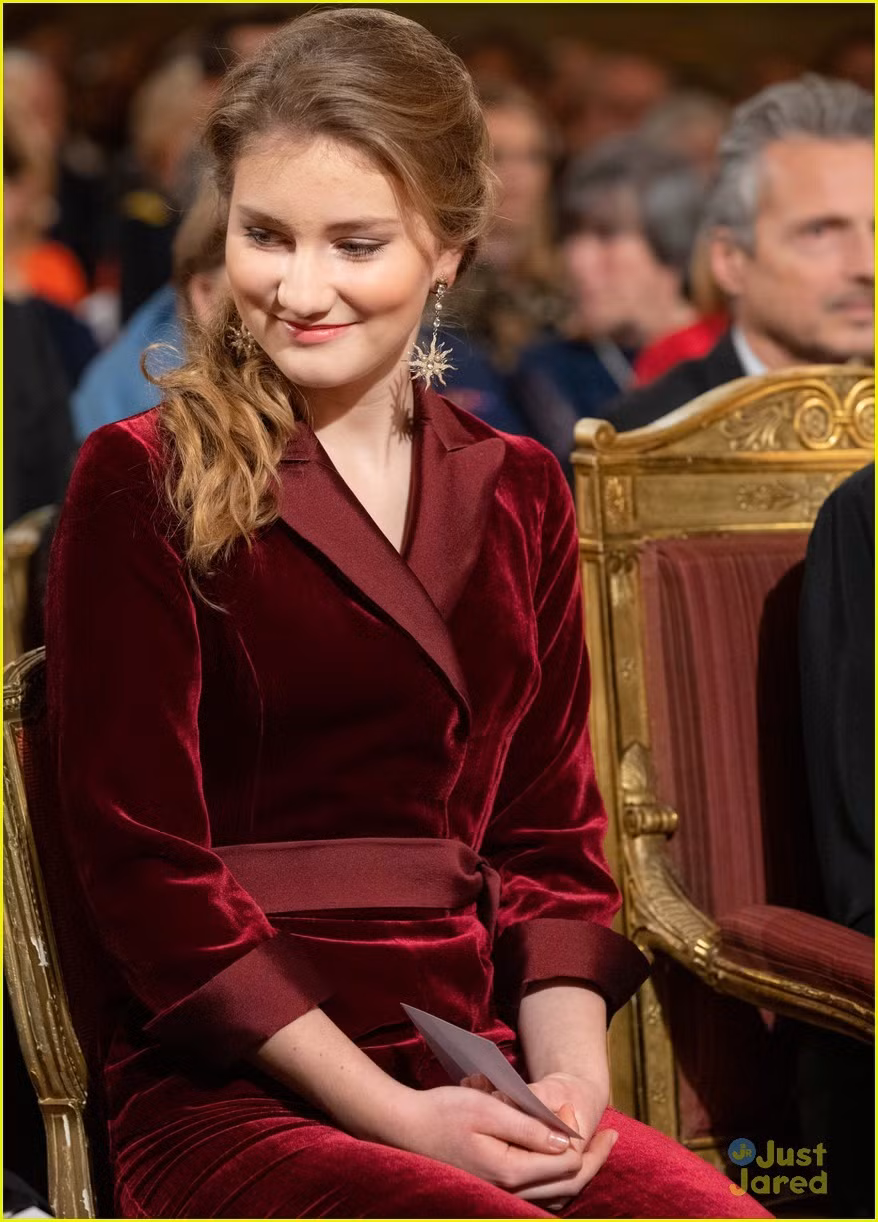 Công chúa Elizabeth mặc một váy nhung màu đỏ rượu vang sang trọng có viền ở cổ áo và hai tay.