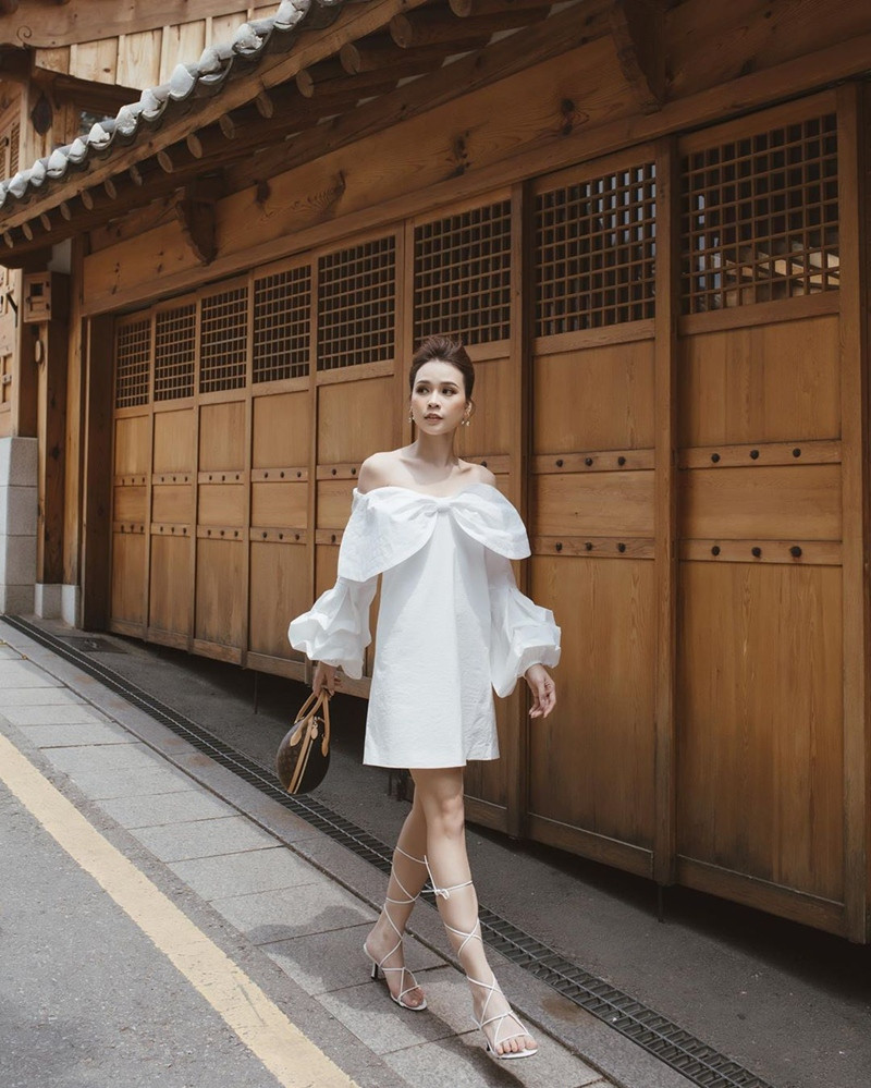 Mỹ nhân Sam xuống phố với bộ đầm trắng trễ vai, thắt nơ trước ngực cùng thiết kế tay bồng yểu điệu.