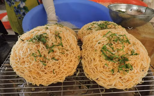 Trước khi chiên, người đầu bếp sẽ tẩm ướp sợi hủ tiếu tươi cùng một ít bột nêm và tiêu xay nhuyễn, sau đó cuộn lại thành bánh rồi đem chiên trên chảo dầu sôi. Đó là bí quyết để làm nên sợi hủ tiếu thơm giòn, có vị mằn mặn, rất vừa ăn.