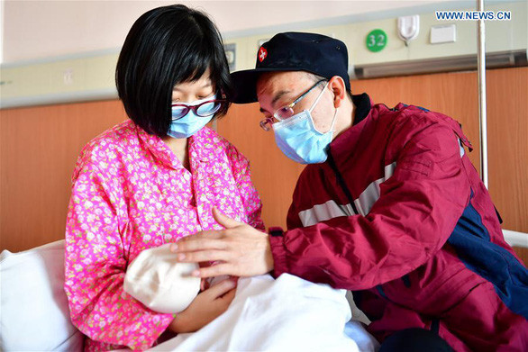 Anh Hao Tiedan (phải) chia tay với vợ Zhang Saihong và con gái vừa chào đời được 2 ngày trước khi lên đường đến vùng dịch corona ở Hồ Bắc hỗ trợ. Ảnh: Tân Hoa Xã Video "Cập nhật 10/2: Số ca tử vong do nhiễm virus corona tăng lên 910". Nguồn: VTC Now.