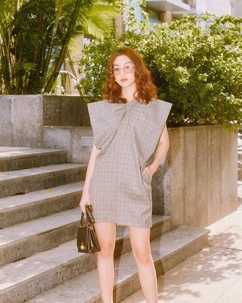 Hoa hậu Đỗ Mỹ Linh trông rất thanh lịch và sang chảnh với chiếc đầm kẻ kiểu dáng chiếc nơ phối cùng chiếc túi xách đen sang trọng. Ảnh: Internet.