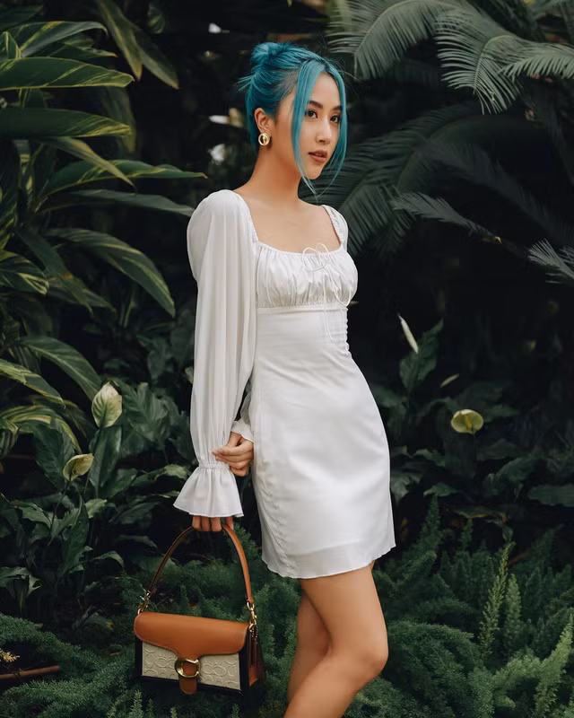 Dù xanh lá là gam màu khá khó mặc, dễ dàng "dìm" những cô nàng da ngăm nhưng cũng chẳng làm khó được Quỳnh Anh Shyn. Mái tóc nhuộm xanh sành điệu được cô mix cùng chiếc đầm trắng tay phồng cổ tích tôn lên vòng eo thon thả.