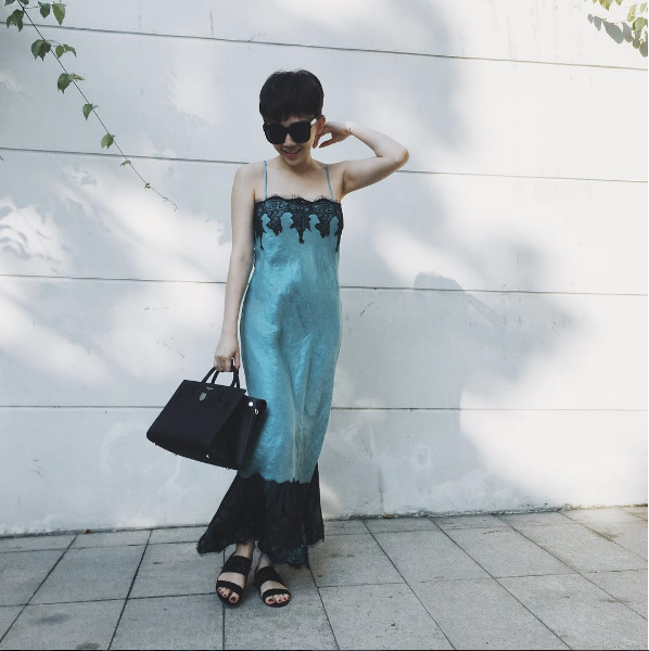 Cô diện chiếc váy ngủ màu xanh ngọc với đường viền ren tinh tế ở chân váy và ngực kết hợp cùng đôi sandals bệt quay ngang và túi xách to bản.