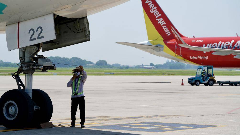 Nhân viên làm việc trong khu bay phải trang bị kín mít để chống chọi với cái nắng thiêu đốt.