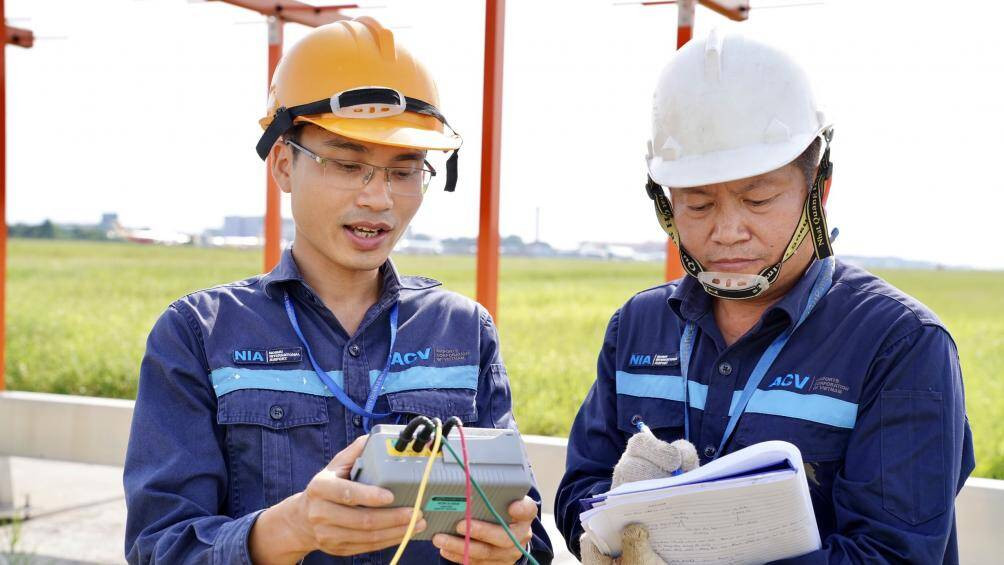 Hai nam nhân viên đang kiểm tra thiết bị dẫn đường khu bay dưới cái nóng gay gắt.