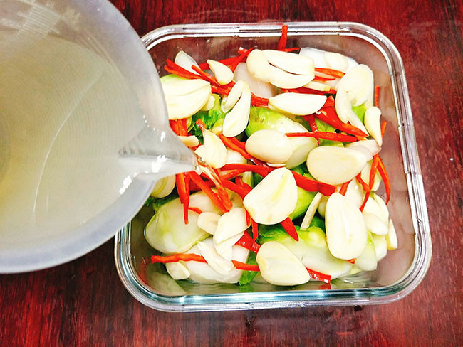 Cách làm: Sơ chế rau mầm đá rồi tiến hành thái vát. Tùy theo thời gian muối chua sớm muộn mà tiến hành thái rau mỏng, dày tương ứng. Rửa qua nước để ráo. Bóc vỏ tỏi. Ớt bỏ hạt, thái chỉ.