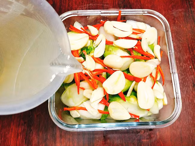 Cách làm: Sơ chế rau mầm đá rồi tiến hành thái vát. Tùy theo thời gian muối chua sớm muộn mà tiến hành thái rau mỏng, dày tương ứng. Rửa qua nước để ráo. Bóc vỏ tỏi. Ớt bỏ hạt, thái chỉ.