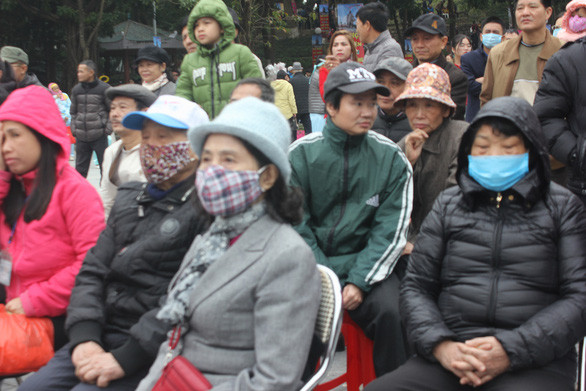 Trước mối lo ngại lây nhiễm virus corona, nhiều người dân tham dự lễ hội Gò Đống Đa với chiếc khẩu trang trên mặt. Ảnh: Tuổi Trẻ.