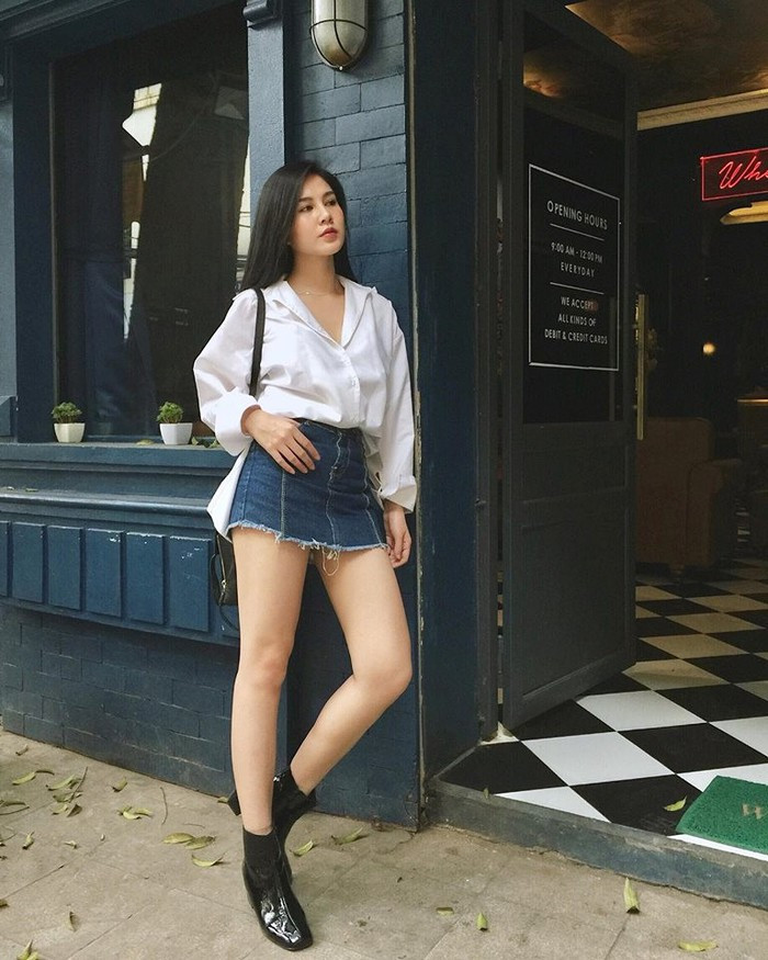 Áo sơ mi trắng và váy jean ngắn khoe đôi chân dài trắng nõn.