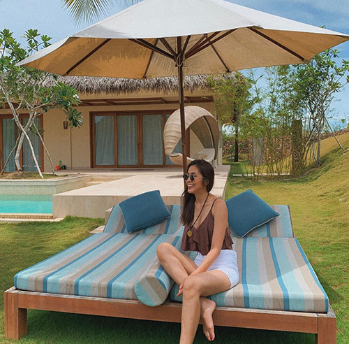 Khi đi nghỉ dưỡng, người đẹp 8X khoe dáng với set đồ gồm áo hai dây bèo nhún, short jeans kiểu lưng cao.