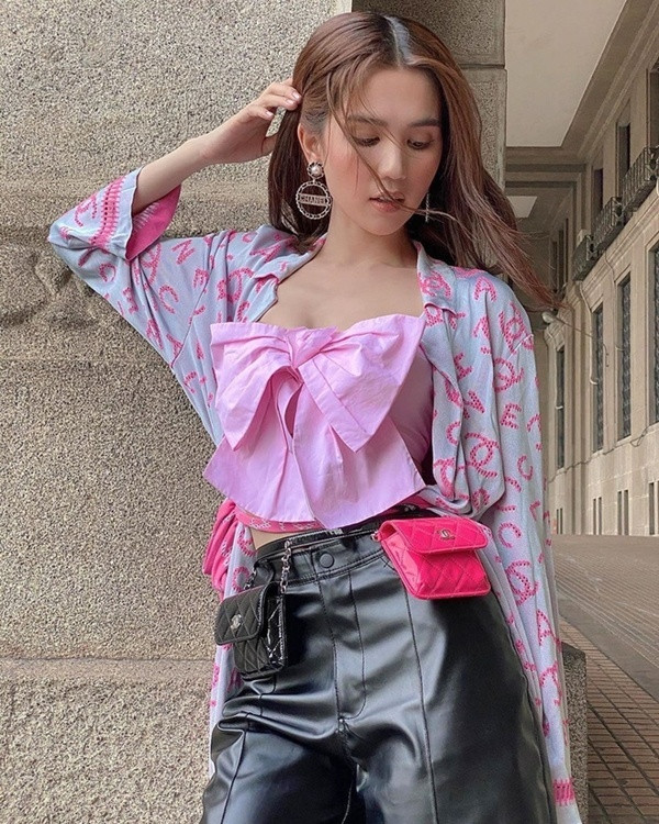 Cùng diện áo nơ nhưng Ngọc Trinh lại trông kém sang khi chọn chiếc áo tông hồng mix cùng quần da bóng dài trên gối màu đen, khoác áo tím có in logo thương hiệu Chanel.
