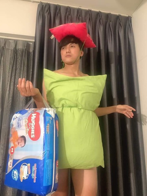 Nam diễn viên Quách Ngọc Tuyên "bắt trend" như tấu hài với chiếc gối màu xanh non phối cùng túi xách là bịch tã giấy của trẻ sơ sinh trên tay và chiếc mũ là chiếc gối đỏ.