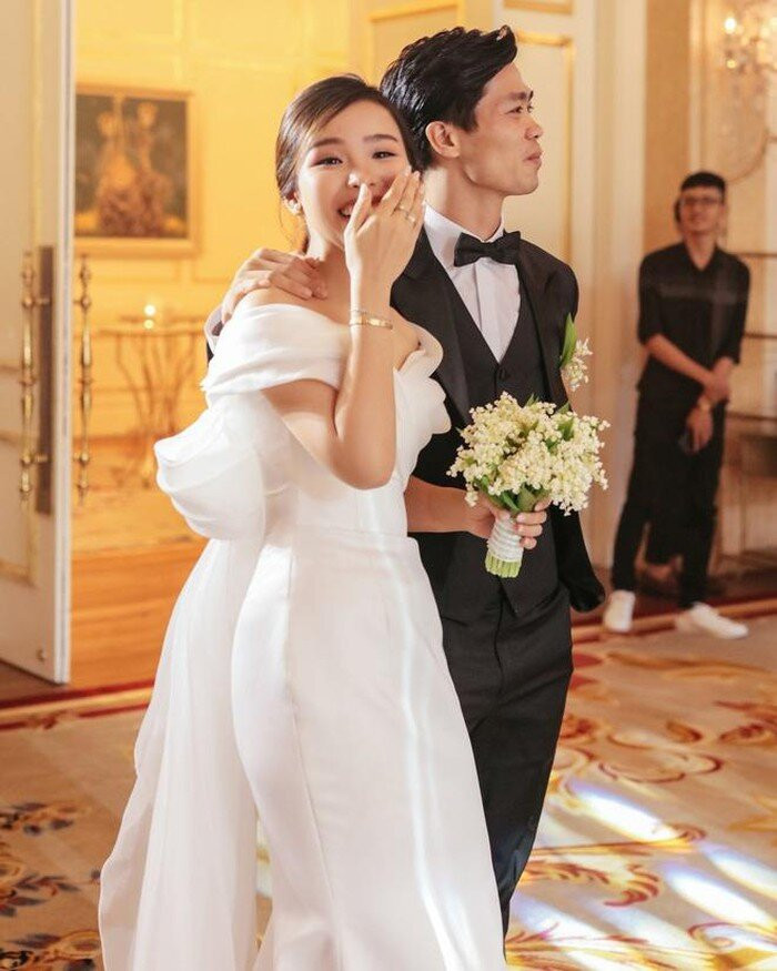 Chiếc váy đính hôn của cô dâu Viên Minh là thiết kế dáng đuôi cá trễ vai vừa trang nhã, vừa giúp cô khoe bờ vai thon thả. Đây là một sáng tạo của NTK Linh Nga, theo phong cách cổ điển những năm 50-60. Phần vai váy được làm từ vải xếp nếp, tạo thành một chiếc nơ lớn ở phía sau làm điểm nhấn.