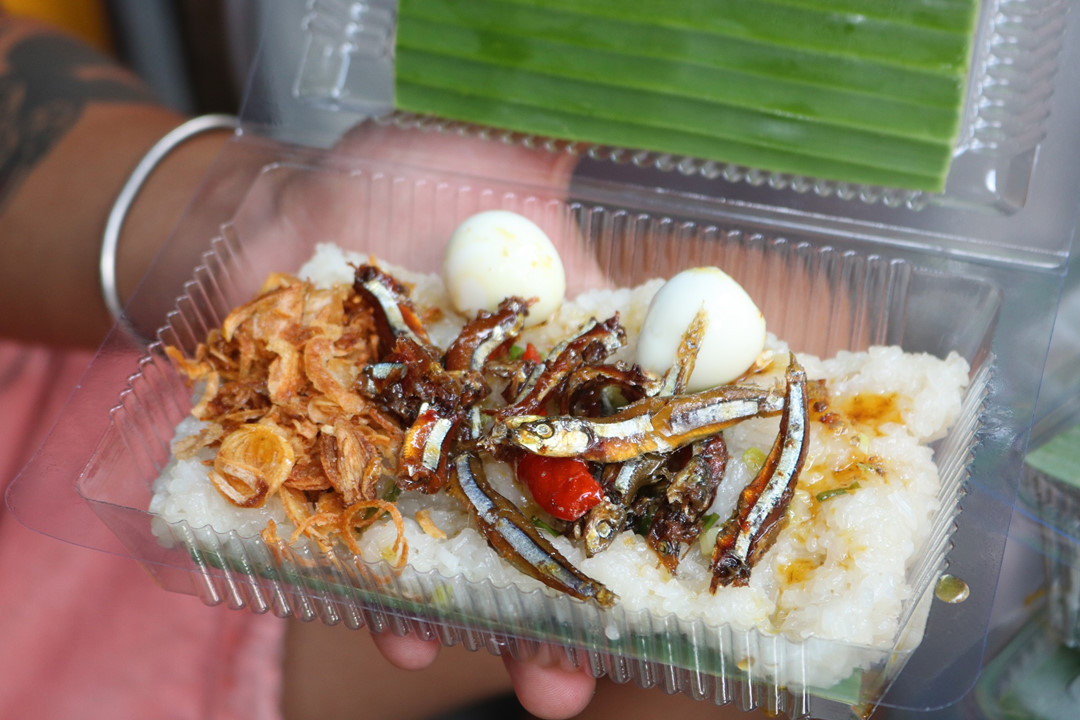 Nồi xôi còn nóng hổi, tỏa khói nghi ngút, mùi thơm từ nếp, từ đậu lan tỏa ra khiến bạn chỉ mới ngửi thôi nhưng trong lòng đã muốn ăn ngay. Xôi được để vào trong hộp, cá cơm rim được để lên phía trên, thêm một ít hành phi, mỡ hành nóng rưới lên trên càng làm tăng thêm hương vị cho món ăn.