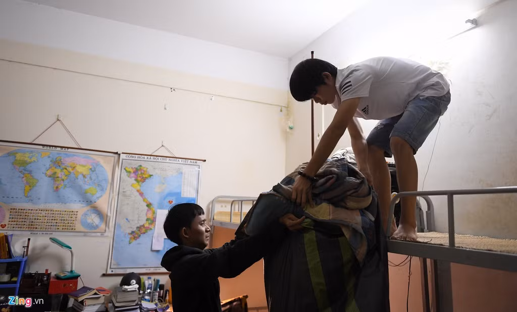 Ở nhà D1, Duy Tiến (bên trái, sinh viên khoa Lịch sử, Đại học Khoa học Xã hội và Nhân văn, Đại học Quốc gia Hà Nội) đang cùng bạn dọn đồ để đón thêm người mới vào ở cùng. Tiến cho biết từ khi có dịch, phòng chỉ có 2 người do những bạn khác đã về quê hết. Tiến quê ở Kiên Giang, việc di chuyển khó khăn nên đành ở lại.