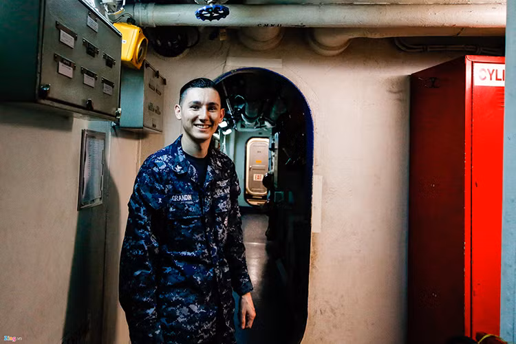 Hình ảnh bên trong một hành lang nối liền các khoang trên tàu sân bay USS Carl Vinson. Trong ảnh là thủy thủ Grandin, 27 tuổi, đã theo tàu 3 năm. Anh cho biết anh đã kết hôn và có một con trai. Nguồn ảnh: Zing News.
