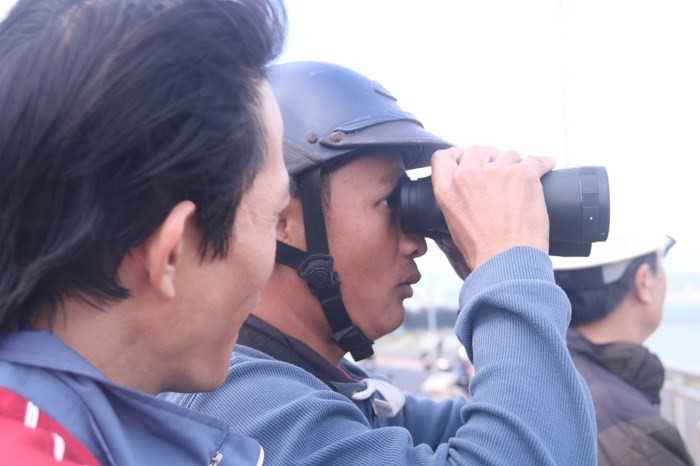 Một người dân tập trung cao độ vào việc quan sát tàu sân bay bằng ống nhòm. Bên cạnh, một người dân khác đang chờ đến lượt mình được xem. Ảnh Nguyễn Thành