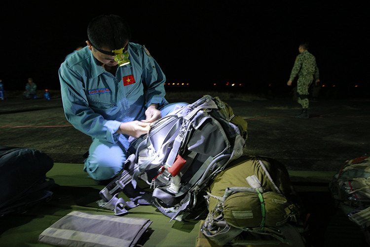 Cận cảnh một người lính sử dụng đèn pin gói buộc đồ cá nhân khi trời còn chưa sáng rõ.