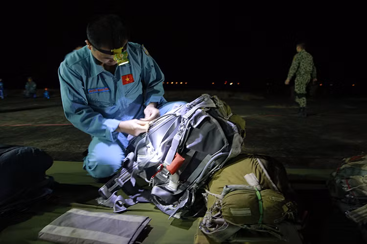 Cận cảnh một người lính sử dụng đèn pin gói buộc đồ cá nhân khi trời còn chưa sáng rõ.