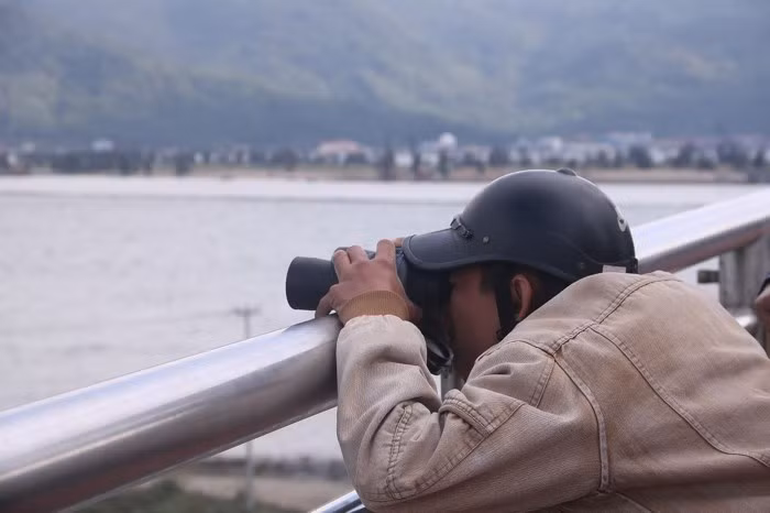 Để quan sát rõ nét tàu sân bay, một người dân kê ống nhòm lên làn can cầu để lấy nét và điều chỉnh cự ly quan sát. Quy mô, kích thước cũng như số lượng máy bay chiến đấu trên tàu sân bay USS Carl Vinson khiến người dân không khỏi thích thú và choáng ngợp. Ảnh Nguyễn Thành