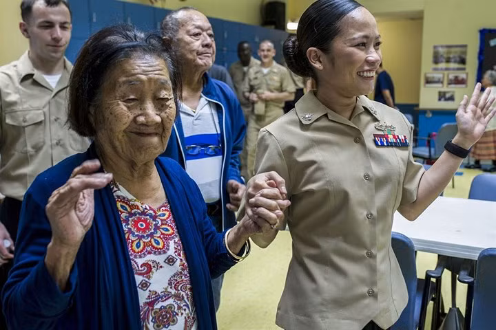 Hạ sĩ quan Charmaine Cruz khiêu vũ với một cụ bà trong 1 dự án cộng đồng ở Guam.