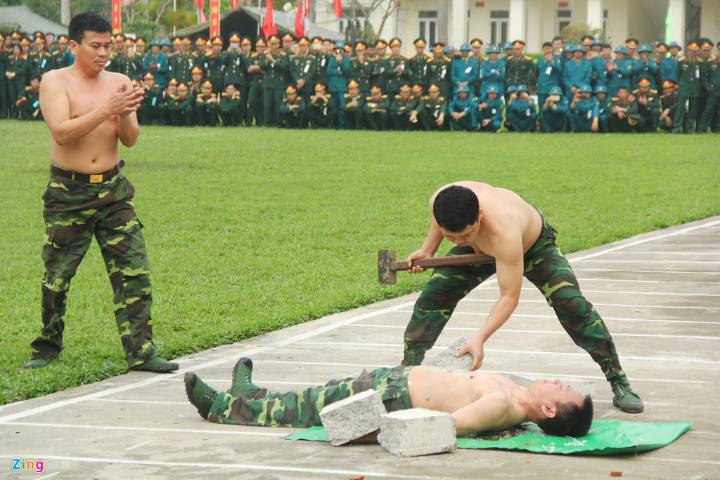 Đại tá Nguyễn Mạnh Trường năm nay hơn 50 tuổi, biểu diễn liên tục nhiều màn võ thuật. Trong ảnh, ông tiếp tục nằm trên mảnh chai để đồng đội chồng bê tông lên người dùng búa đập vỡ.