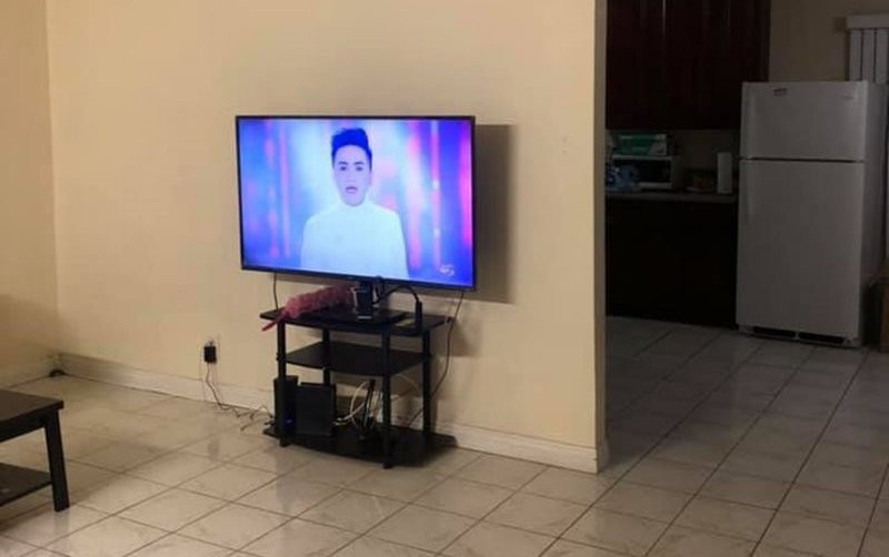 Phòng khách có 1 chiếc tivi nhỏ, thêm 1 bộ bàn ghế tiếp khách gỗ. Bên cạnh là phòng ăn và nhà bếp, tuy nhà đầy đủ tiện nghi nhưng không phải quá sang trọng.