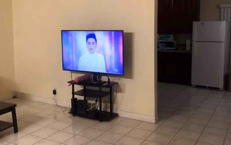 Phòng khách có 1 chiếc tivi nhỏ, thêm 1 bộ bàn ghế tiếp khách gỗ. Bên cạnh là phòng ăn và nhà bếp, tuy nhà đầy đủ tiện nghi nhưng không phải quá sang trọng.