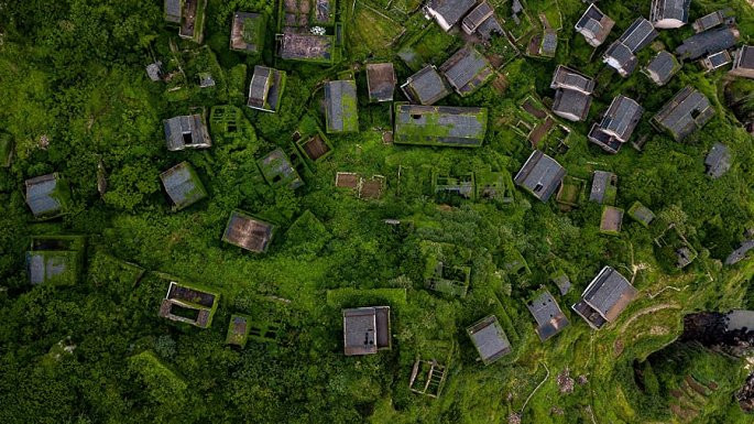 Năm 2002, sự suy giảm dân số khiến ngôi làng phải sáp nhập vào một ngôi làng gần đó. Sau nhiều thập kỷ bị bỏ hoang, những ngôi nhà trong làng phủ xanh bởi những cây leo tươi tốt. (Ảnh: CNN)
