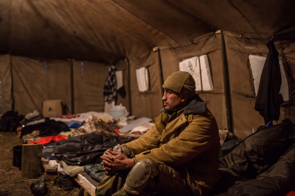 Oleksandr, một nhà hoạt động xã hội không muốn nêu họ, ngồi bên trong lán trại tại điểm chặn đoàn tàu chở than ở làng Shcherbynivka. Ảnh USN