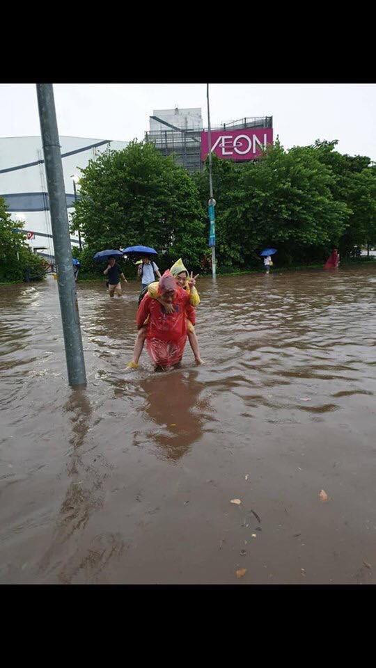 Người đi bộ cõng nhau khi nước đã ngập đến đầu gối.