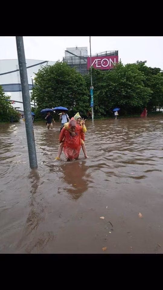 Người đi bộ cõng nhau khi nước đã ngập đến đầu gối.