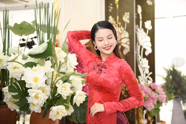 Vợ Chí Anh nổi bật với áo dài nhung đỏ bên sen trắng.