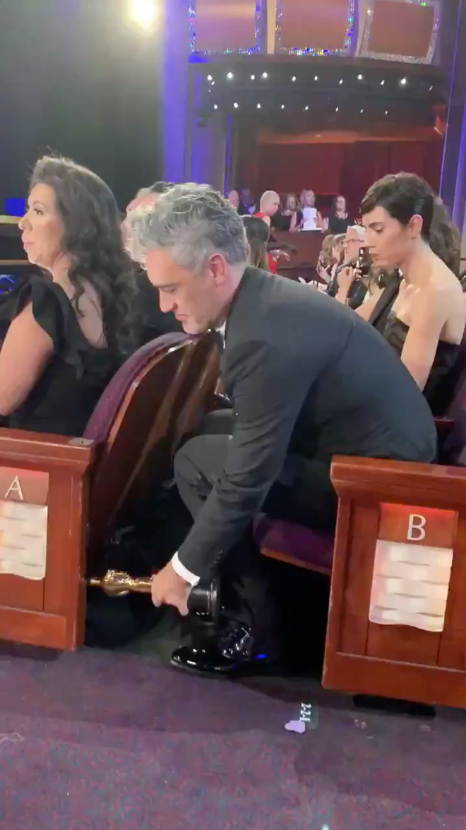 Đạo diễn Taika Waititi sau khi đoạt tượng vàng Oscar với hạng mục Kịch bản chuyển thể xuất sắc cho bộ phi hài kịch Jojo Rabbit. Nam đạo diễn đã chọn cách giấu tượng vàng dưới ghế khiến mọi người phải bật cười.