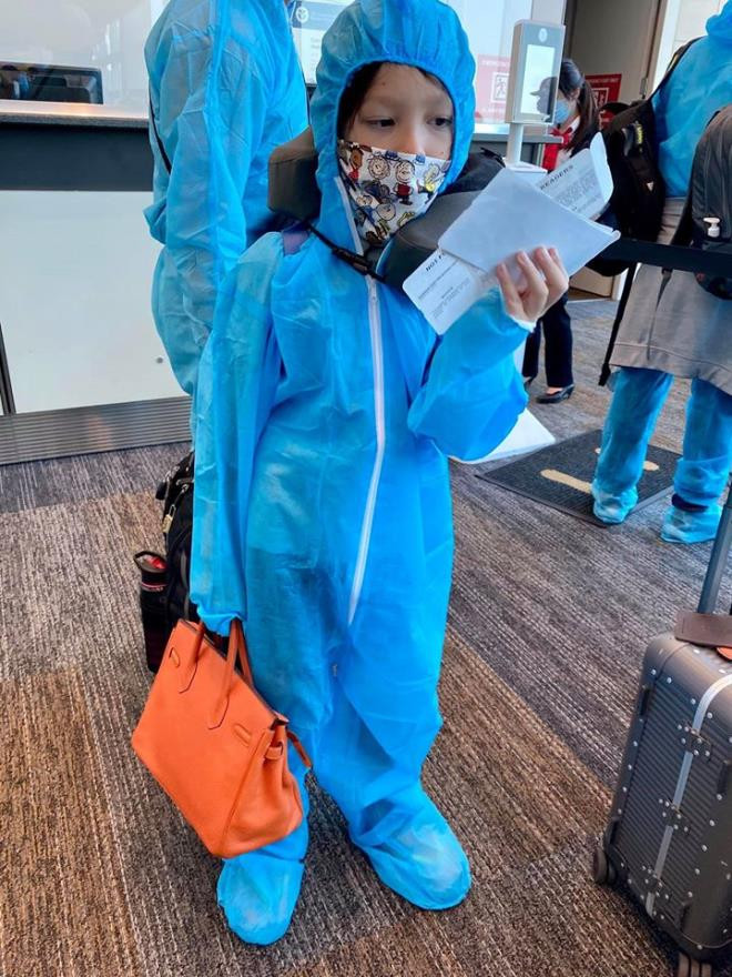 Hình ảnh các con của Hồng Nhung khi lên máy bay về Việt Nam. Bé Tôm gọi bộ trang phục bảo hộ là "bộ đồ phi hành gia".