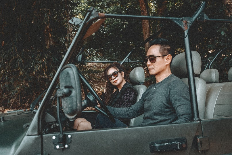 Vợ chồng đạo diễn diện trang phục đen năng động, tạo dáng bên xe jeep và khung cảnh núi rừng. Kết hôn 10 năm và có 4 người con nhưng 2 vợ chồng vẫn khiến nhiều người ngưỡng mộ vì luôn mặn nồng như thuở ban đầu.