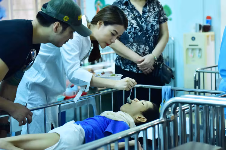 Trương Ngọc Ánh ân cần bón cơm cho một em nhỏ. Trong hoạt động này, cô đã thay mặt công ty của mình trao những phần quà có giá trị cho đại diện của trung tâm. 