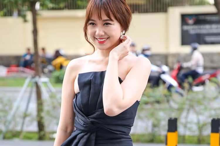 Hari Won diện đầm đen thanh lịch, hở vai trần tới sự kiện. Nữ ca sĩ là khách mời trong chương trình ra mắt sản phẩm mà Trấn Thành làm đại diện. 