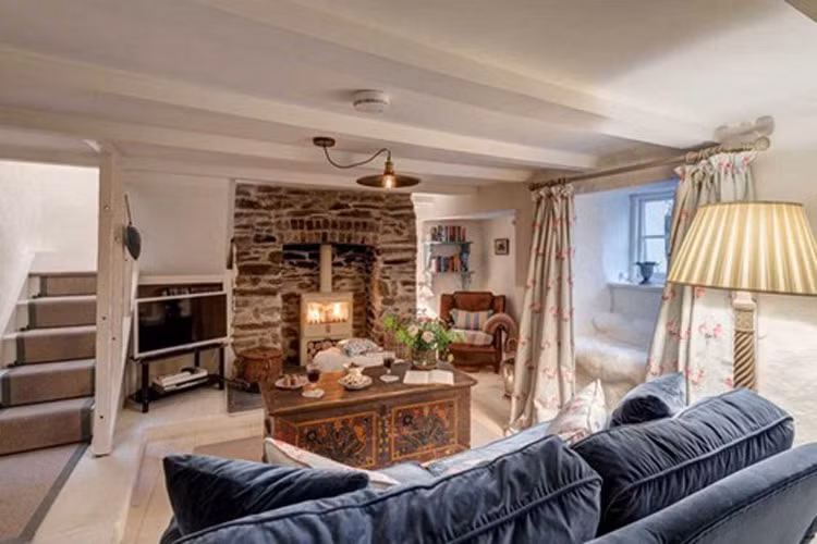 Bên trong nhà, phòng khách có nội thất hiện đại với ghế mềm mại và ấm cúng, TV, lò sưởi và góc đọc sách. 