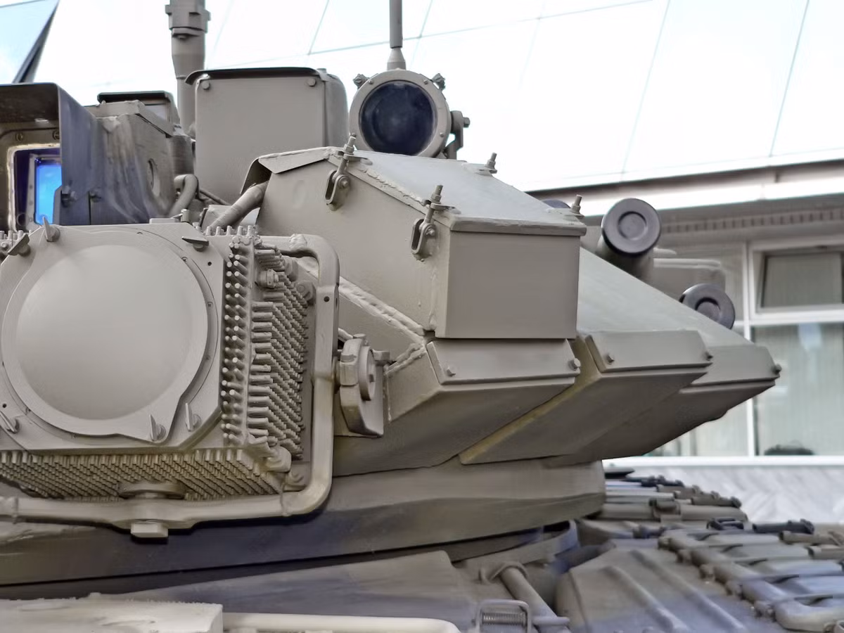 Cận cảnh một trong hai đèn gây nhiễu OTShU-7-1 của tổ hợp phòng vệ chủ động Shtora-1. Hai "con mắt" gắn trên tháp pháo có tác dụng làm giả tín hiệu hồng ngoại, khiến hệ thống điều khiển bắn của tên lửa chống tăng nhầm lẫn giữa tín hiệu tên lửa và Shtora, làm nó đưa ra chỉ dẫn sai cho tên lửa dẫn tới việc tên lửa hoặc là lao đầu xuống đất, hoặc là bay lên trời. Nguồn ảnh: Wikipedia